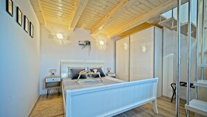Une chambre à coucher moderne avec un lit, des tables de chevet et une grande fenêtre.
