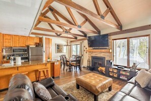 A spacious living area with a fireplace, wooden beams, a kitchen with modern appliances, and leather furniture.