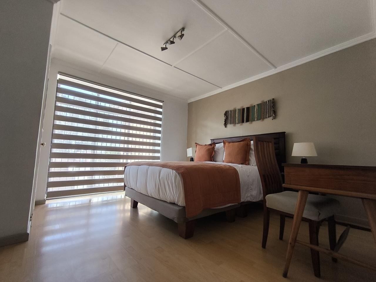 A bedroom with a bed, a desk, and a chair.