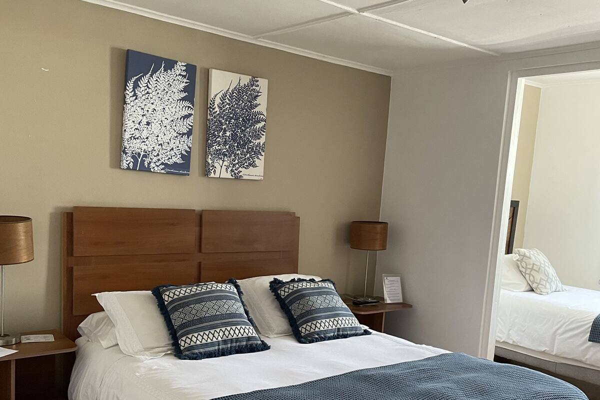 A neatly arranged bedroom with a large bed, two bedside tables, and two wall-mounted lamps.