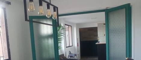 Un salón de conferencias con una larga mesa, sillas de oficina negras y una lámpara colgante.