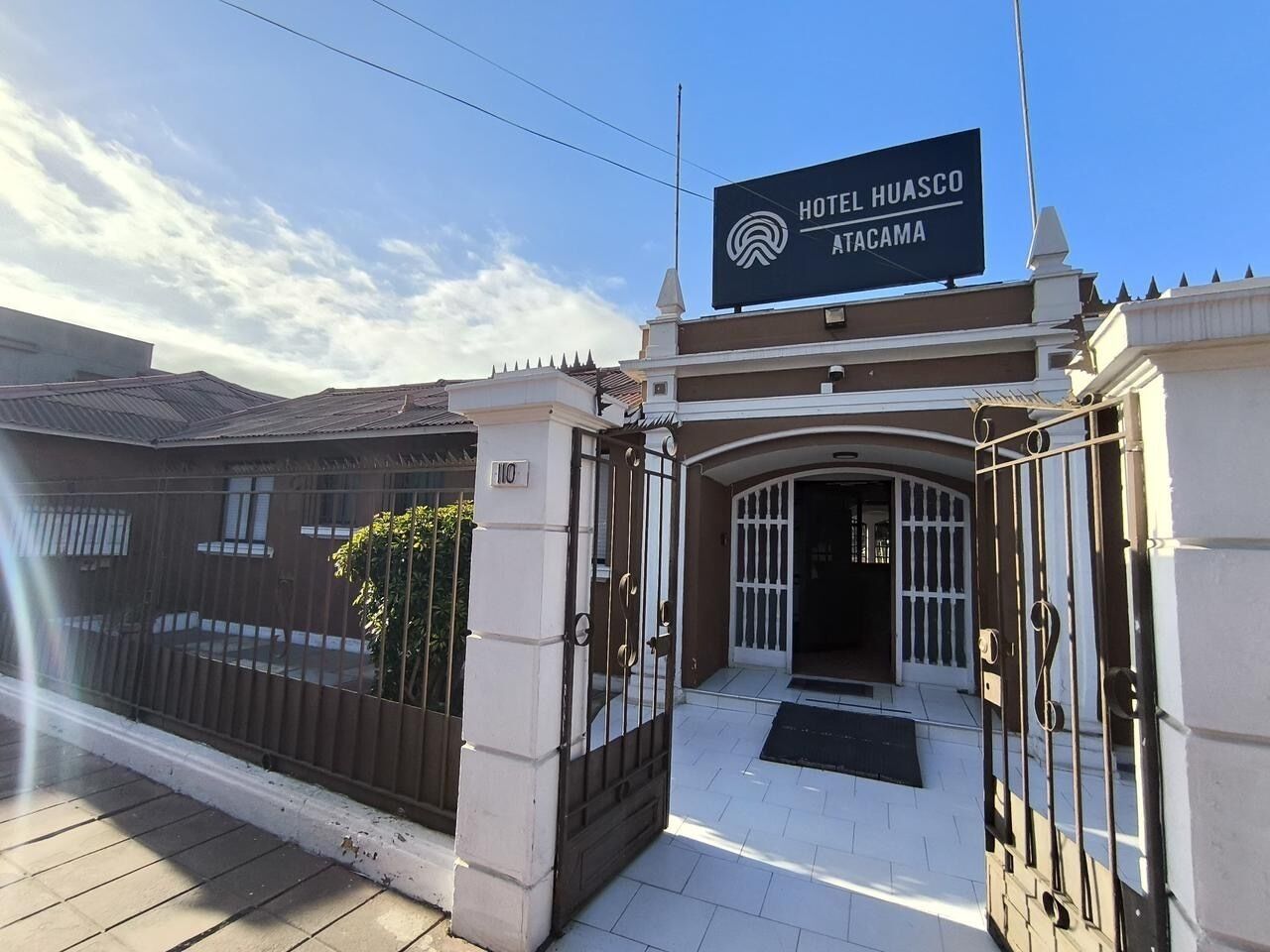 Hotel Huasco Tacama's indgang med en låge og en klar himmel.