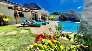 A pool area with lounge chairs and a pergola. - 9BR Superb Villa Sun&Soul at Community beach (Sosúa)