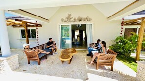 A covered outdoor seating area with wooden furniture and a central round table. - 9BR Superb Villa Sun&Soul at Community beach (Sosúa)