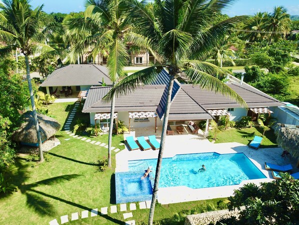 A resort with a swimming pool, lounge chairs, and palm trees. - 9BR Superb Villa Sun&Soul at Community beach (Sosúa)