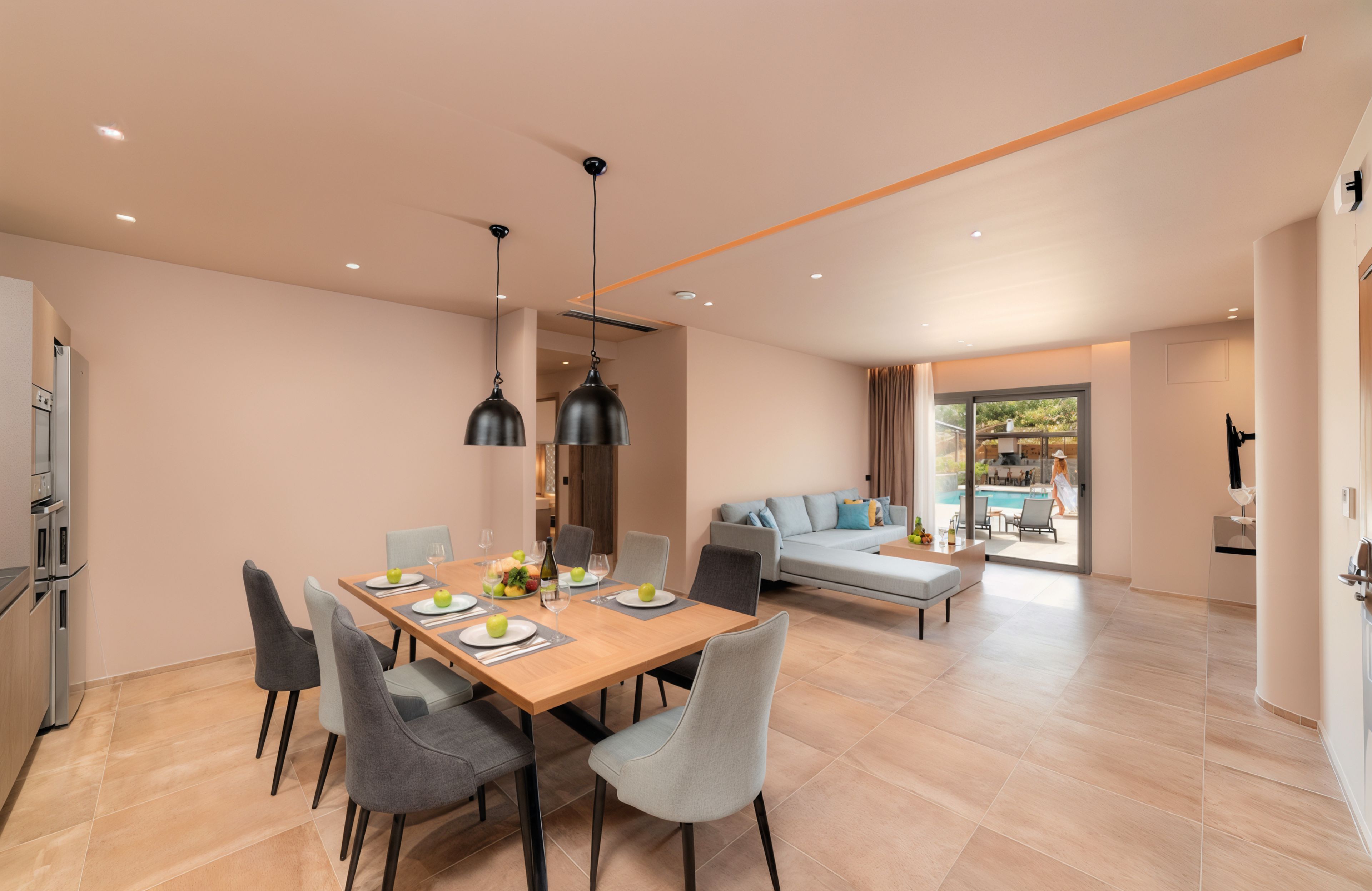 A modern dining area with a wooden table, grey chairs, and a view of a pool through the glass door.