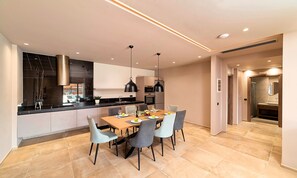 Une cuisine moderne avec un coin repas, comprenant un grand îlot central, des appareils électroménagers intégrés et une vue sur le salon.