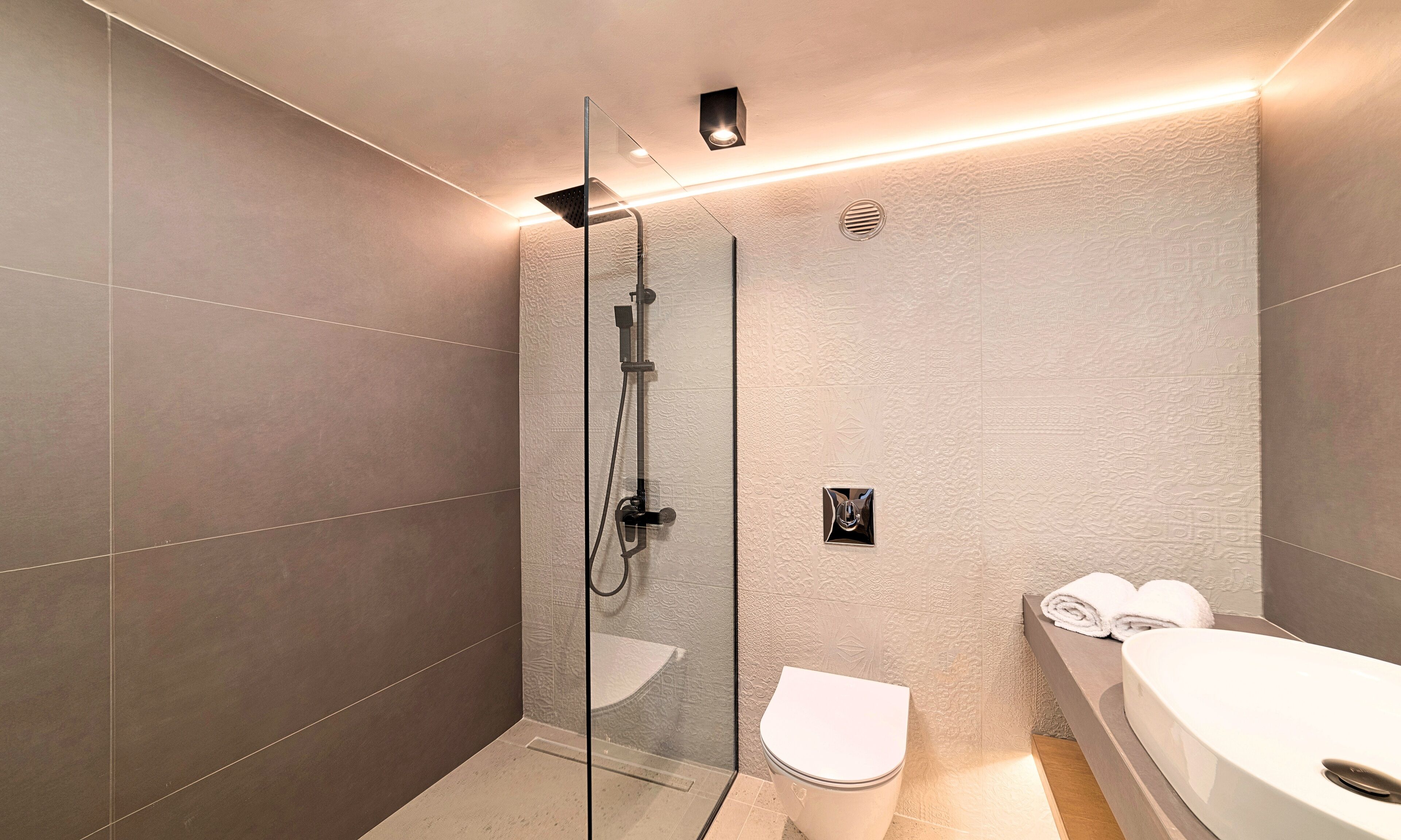 A modern bathroom with a glass-enclosed shower, a toilet, and a bathtub.