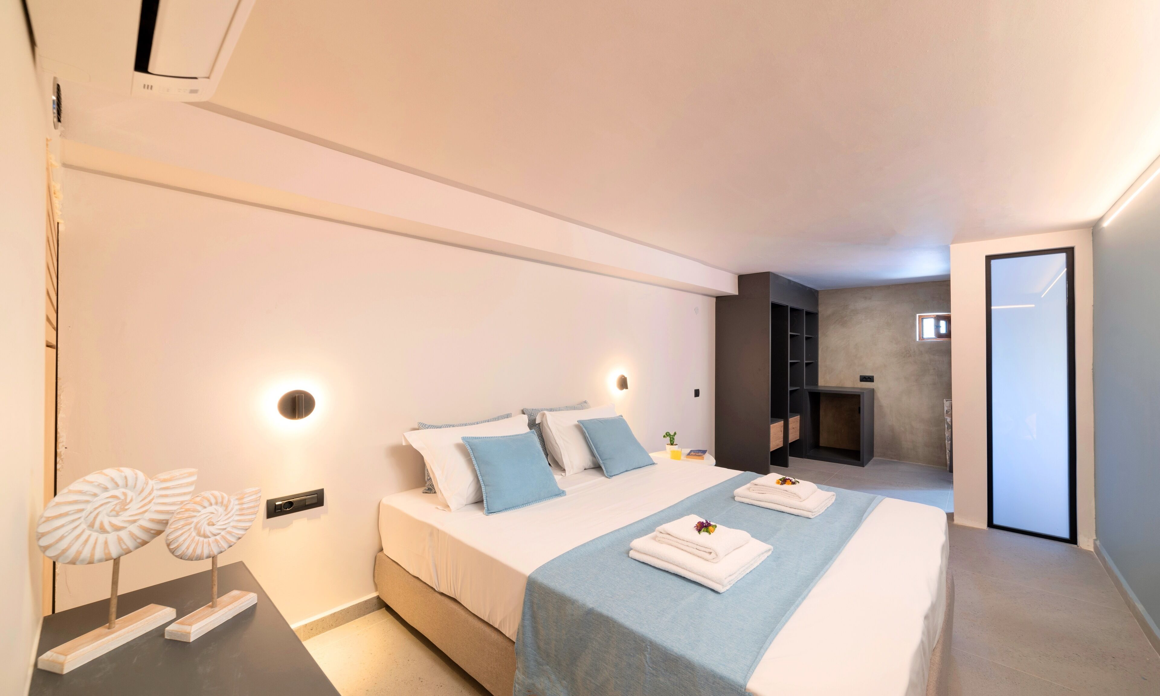 A modern bedroom with a large bed, bedside lamps, and a built-in shelf.