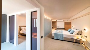 Une chambre d’hôtel moderne avec un grand lit, une petite table de chevet, un climatiseur fixé au mur et une armoire intégrée.