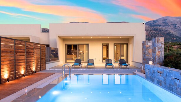 Un espace piscine moderne offrant une vue dégagée sur la piscine, des chaises longues et un mur en pierre.