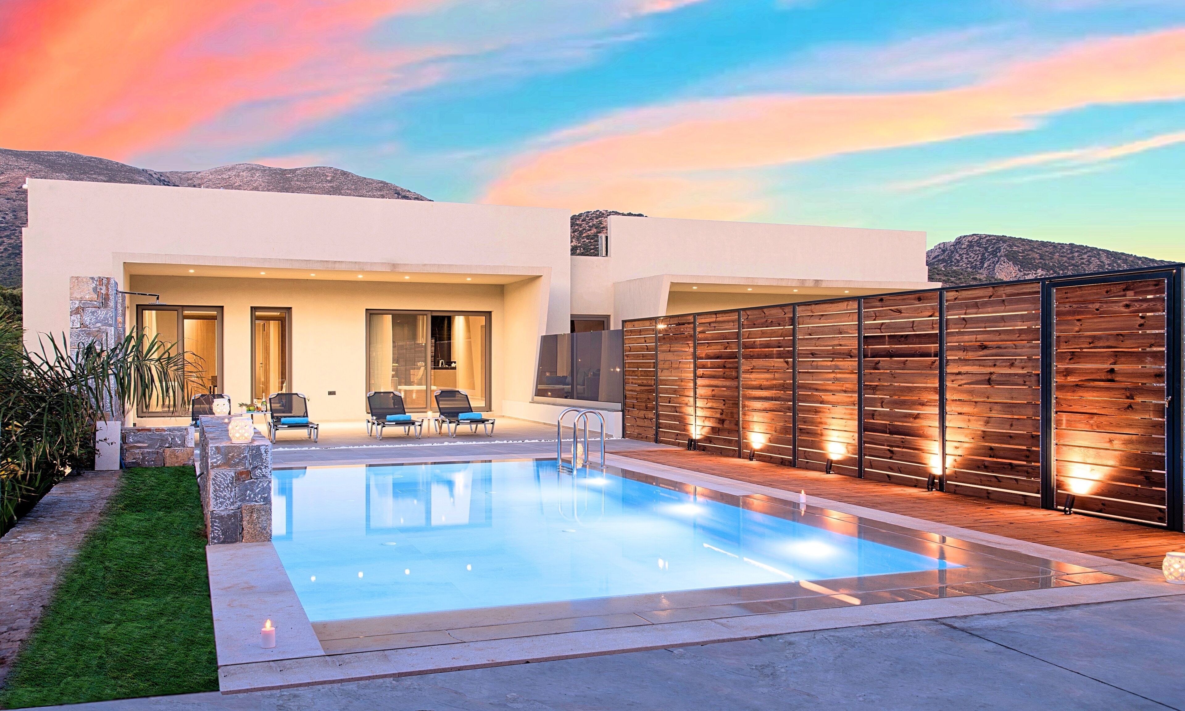 A modern house with a swimming pool, outdoor seating, and a view of the mountains.