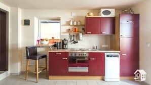 Une cuisine compacte dotée d’un îlot central, d’un four à micro-ondes, d’un réfrigérateur et d’un lave-vaisselle.