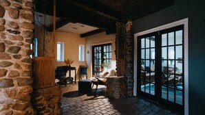 A cozy room with stone walls, a fireplace, a comfortable seating area, and a large window with a view.
