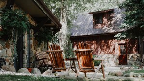 A rustic cabin with stone walls, wooden furniture, and a stone pathway.