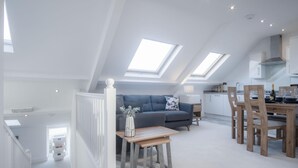 A loft-style apartment with a dining area, kitchen, and living space. - Skylark - 2 Bedroom Apartment - Tenby (Tenby)