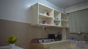A kitchen with a white countertop, a gas stove, a microwave, and a shelf above the counter. - Cozy stay in Langata (Nairobi)