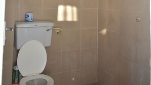 A bathroom with a toilet, a shower head, and a toilet paper dispenser. - Cozy stay in Langata (Nairobi)