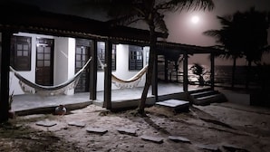 A beachfront property with a covered porch, a hammock, and a view of the ocean. - Pousada Marinheiro (Conde)