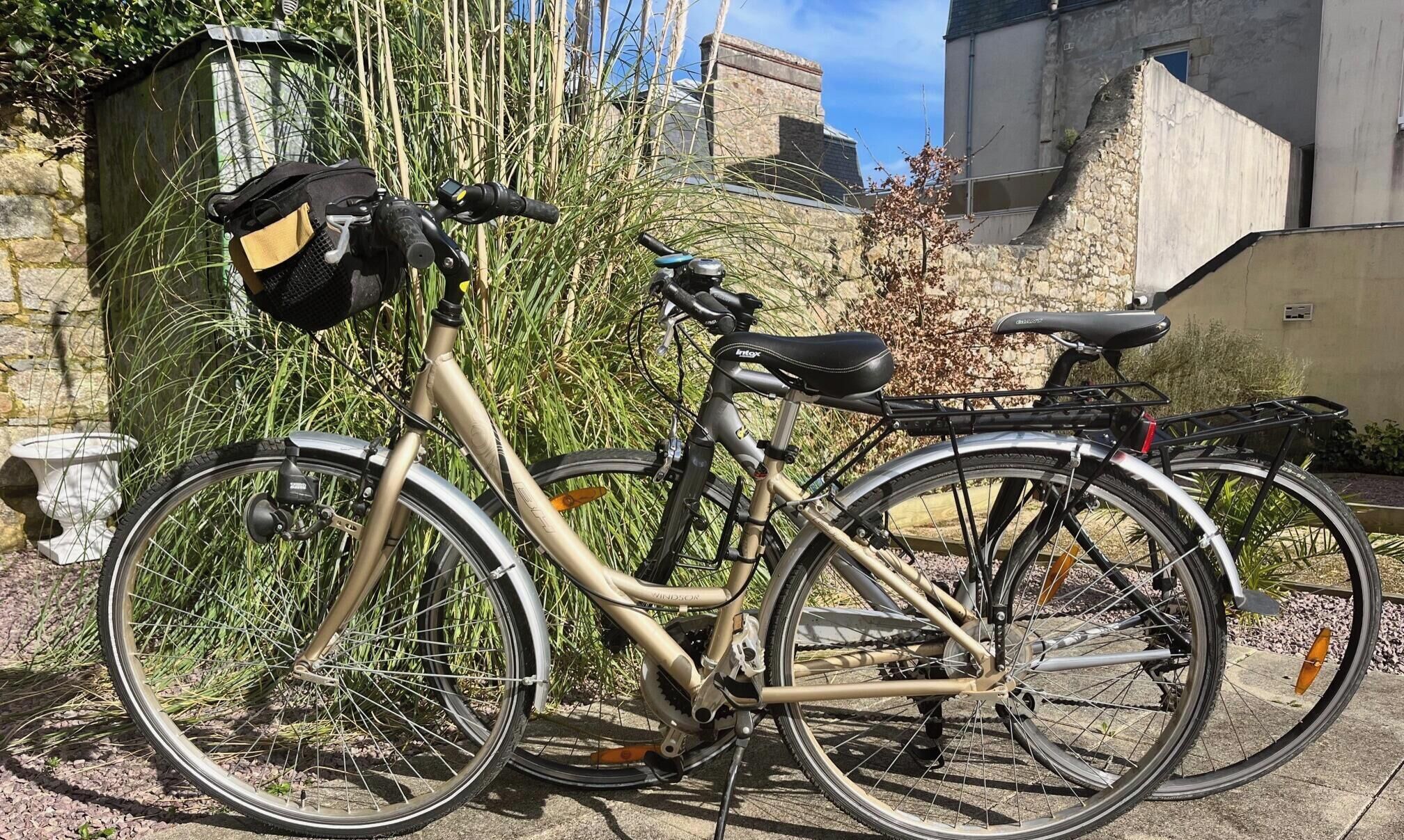Un vélo est garé devant un bâtiment en pierre, avec un jardin.