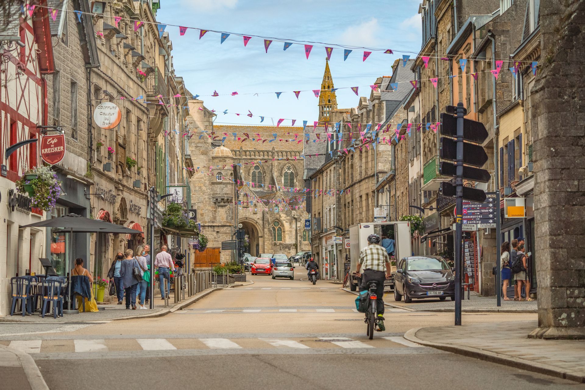 A street with historic buildings, a church, and a cyclist.