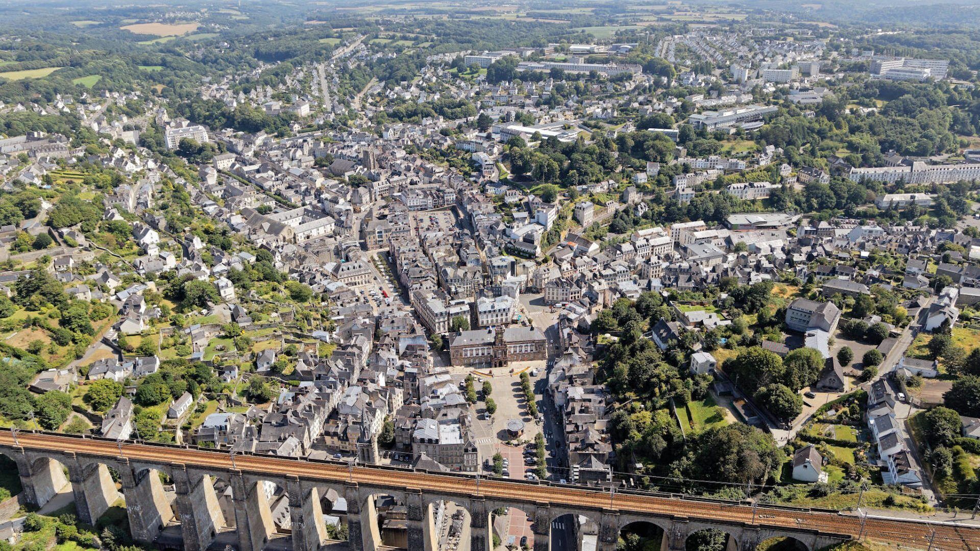 An aerial view of a historic town with a prominent stone bridge in the foreground.