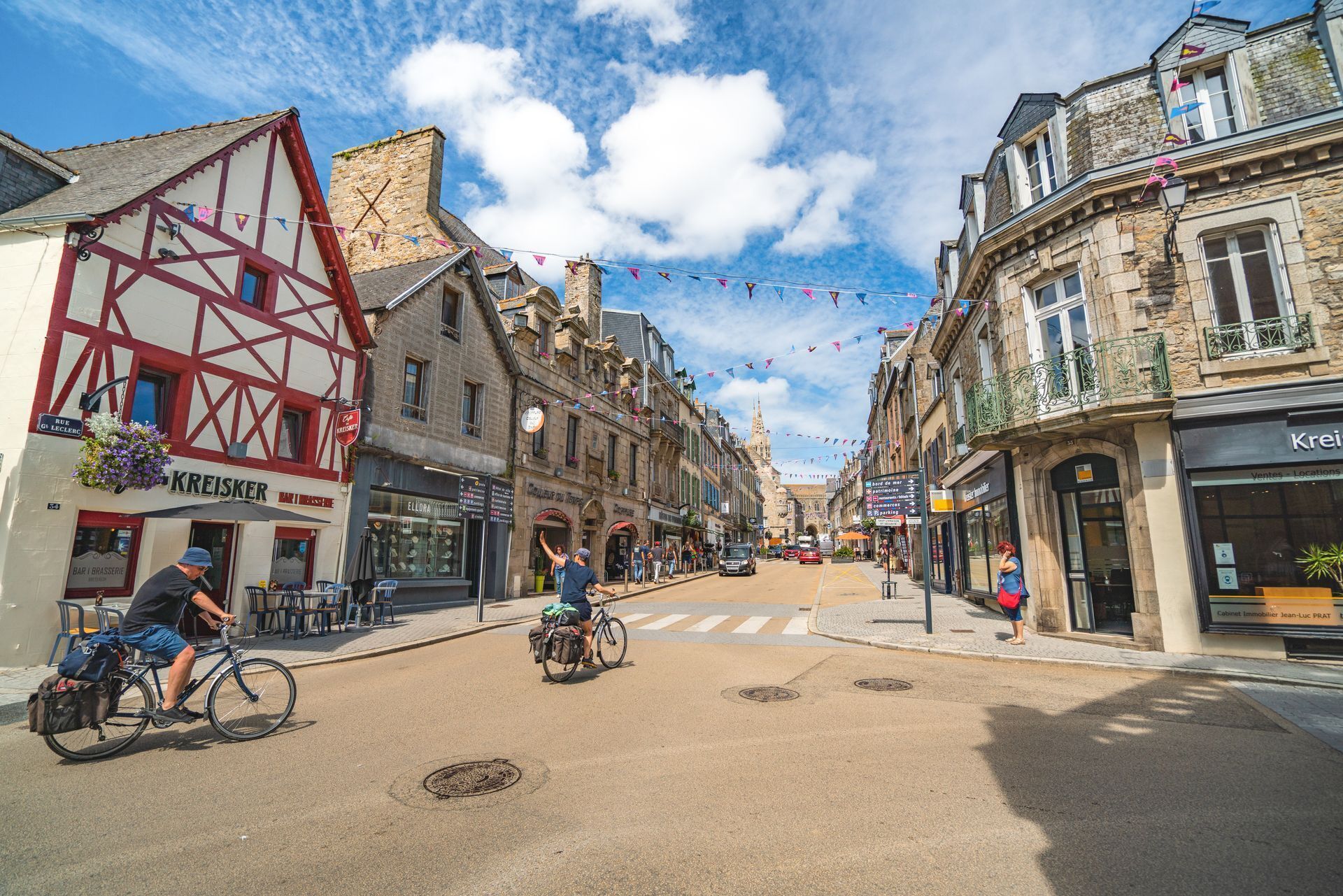 Une rue bordée de bâtiments à l’architecture européenne traditionnelle, notamment des maisons à colombages et des façades en pierre.