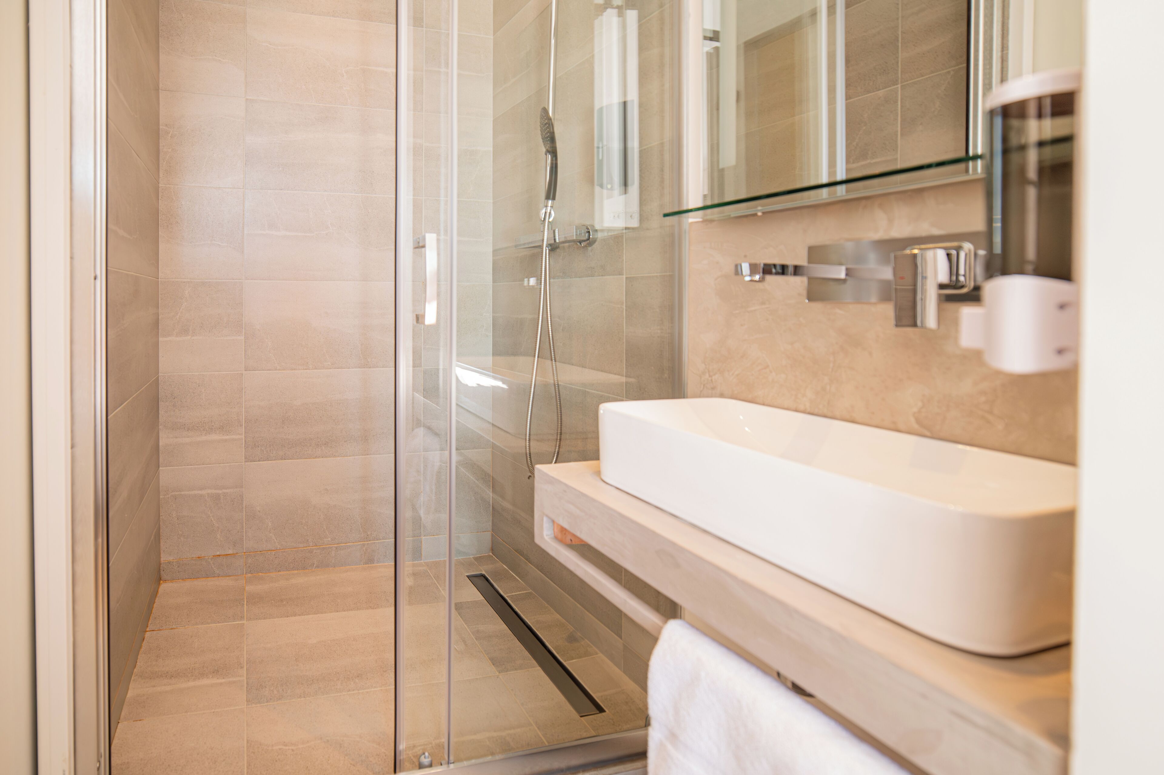 Une salle de bain moderne avec une douche à parois de verre, un lavabo blanc et un miroir au-dessus du lavabo.