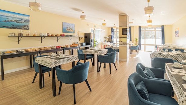 Een eetruimte met meerdere tafels en stoelen, een buffetopstelling en uitzicht op het buitenleven door grote ramen.