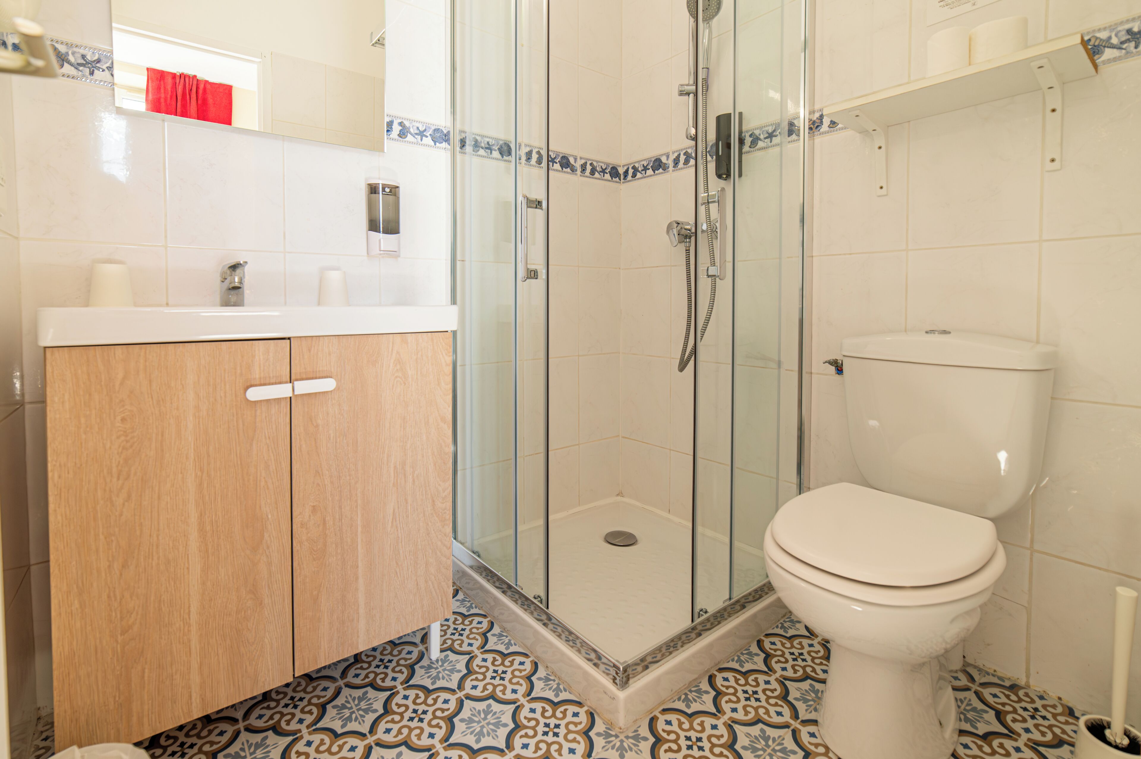 Een badkamer met een glazen douchecabine, toilet en een houten wastafelmeubel met spiegel.