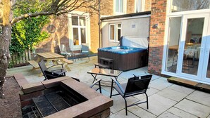 Un jardin avec un jacuzzi, des meubles de patio et un espace barbecue.