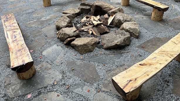 Un foyer entouré de bancs en pierre et en bois.