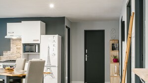 Eine moderne Küche mit einem weißen Kühlschrank, einer Mikrowelle und einem Essbereich mit Tisch und Stühlen.