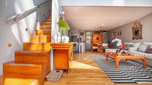 A spacious living area with a staircase, wooden flooring, a coffee table, and a sofa.