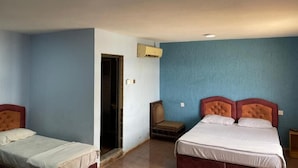 Une chambre avec deux lits, une chaise et un appareil de climatisation.