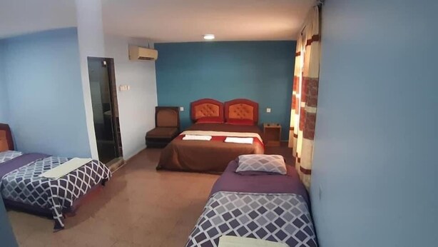 Une chambre d’hôtel avec deux lits simples, un canapé, une petite table et un appareil de climatisation.