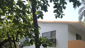 Un edificio con varias ventanas y equipos de aire acondicionado, rodeado de árboles y una escalera.