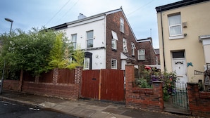 A residential building with a brick facade, a gated entrance, and a small garden with flowers. - Large and spacious 5 bedroom house in the heart of Liverpool (Fairfield)
