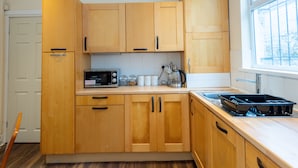 A kitchen with wooden cabinets, a microwave, a coffee maker, and a stove. - Large and spacious 5 bedroom house in the heart of Liverpool (Fairfield)