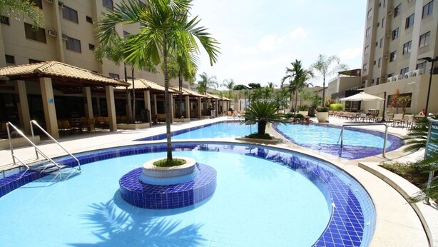 A swimming pool with a circular design, surrounded by lounge chairs and palm trees. - Thermas Boulevard (Caldas Novas)