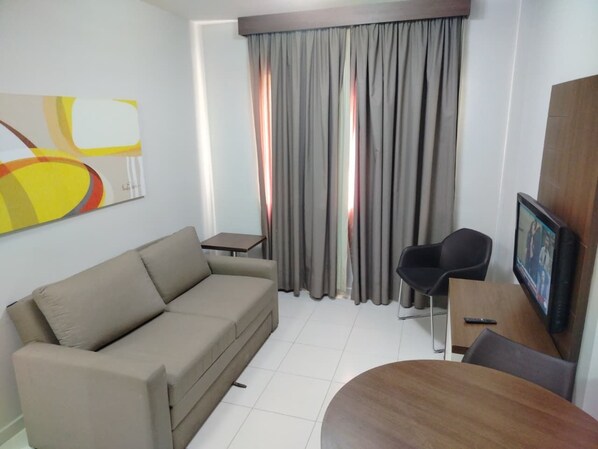 Una sala de estar moderna con un sofá, una mesita, un televisor y una silla.