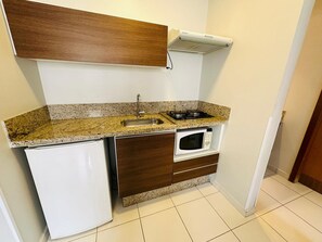 A compact kitchen with a built-in sink, stove, microwave, and a small refrigerator.