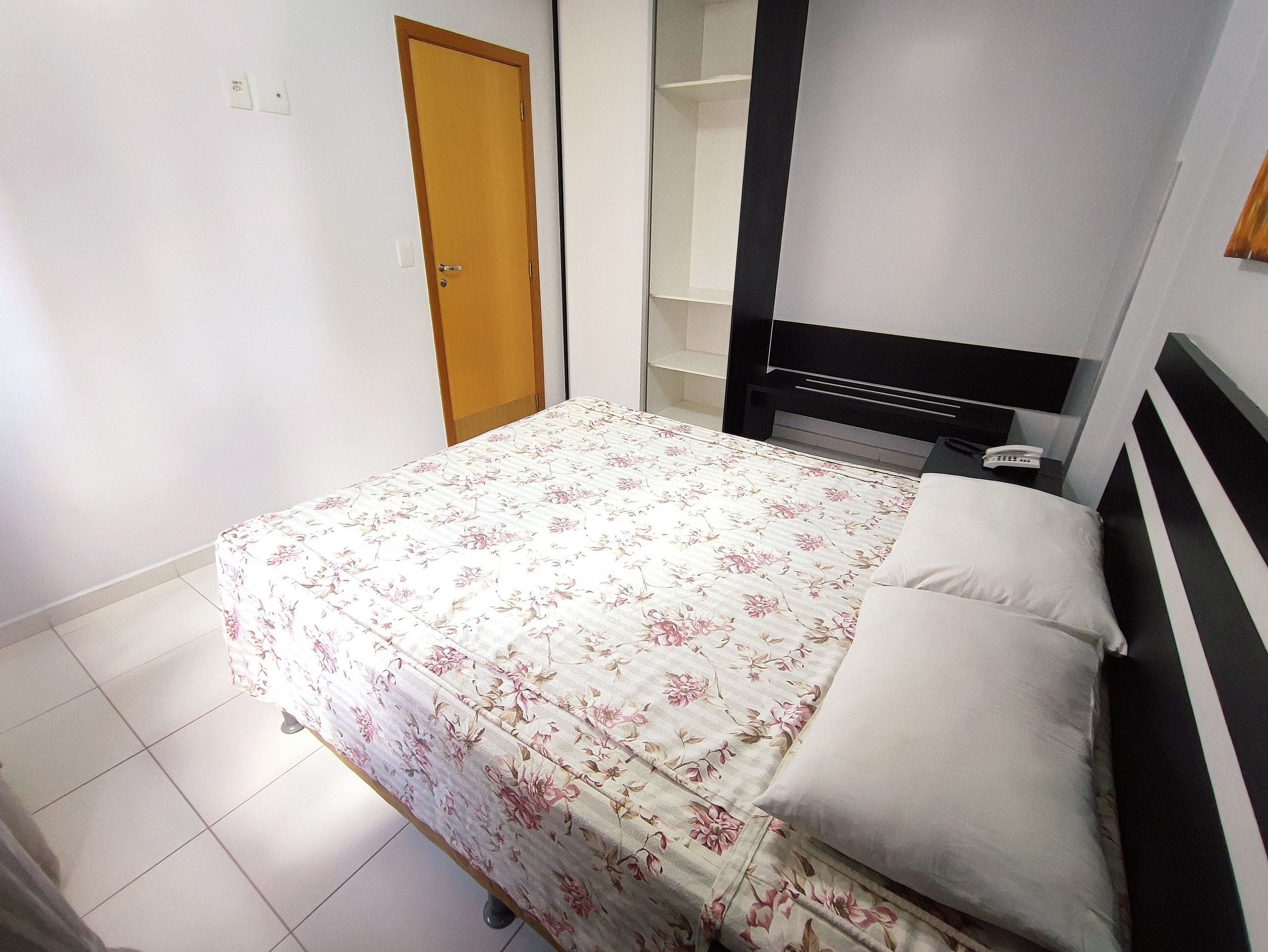 A bedroom with a bed, a wardrobe, and a bedside table with a phone.