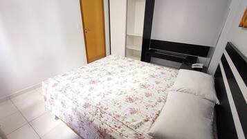 A bedroom with a bed, a wardrobe, and a bedside table with a phone.