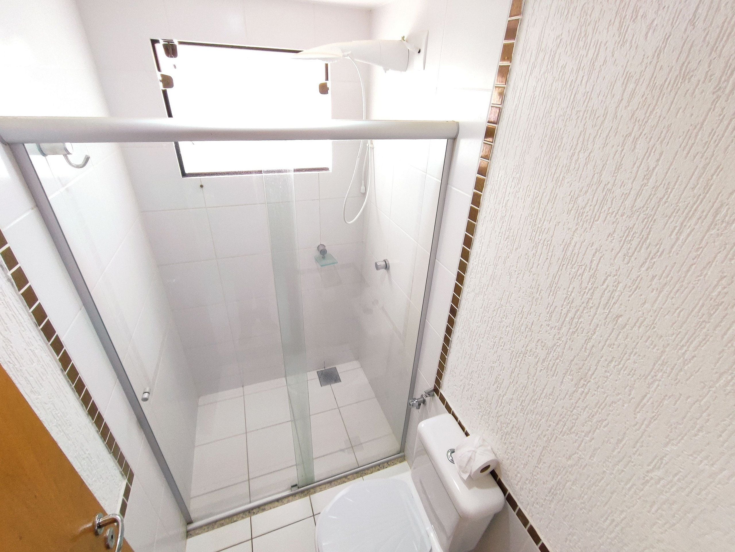 Ein kleines Badezimmer mit Duschkabine, Toilette und Handtuchhalter.