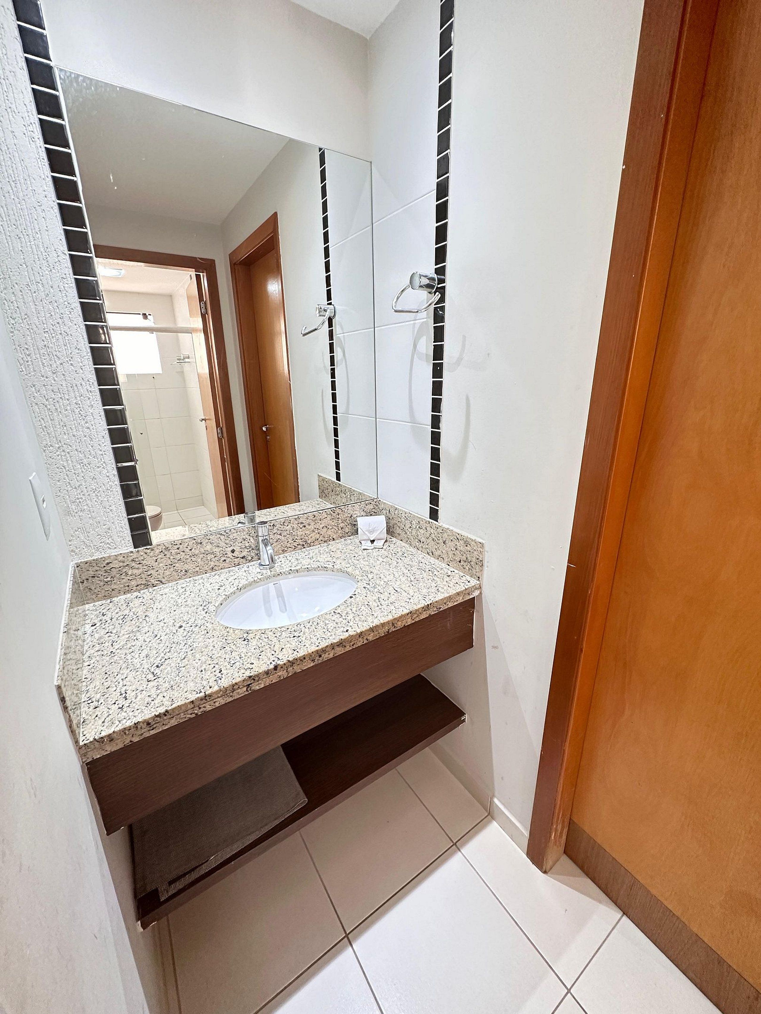 Un baño con lavamanos de encimera de granito, espejo y zona de ducha.