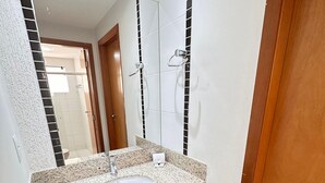A bathroom with a granite countertop sink, a mirror, and a shower area. - Thermas Boulevard (Caldas Novas)