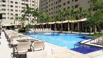 A pool area with lounge chairs, a swimming pool, and palm trees.