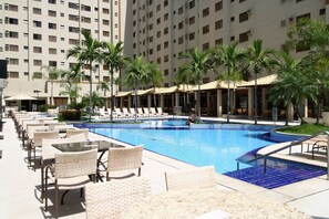 A pool area with lounge chairs, a swimming pool, and palm trees. - Thermas Boulevard (Caldas Novas)