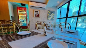 A dining area with tables set for two, a Coca-Cola refrigerator, and artwork on the walls. - Ambassador (João Pessoa)